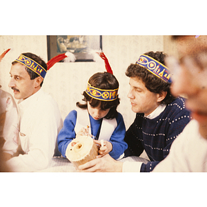 Child being helped with a craft while wearing a feather headband