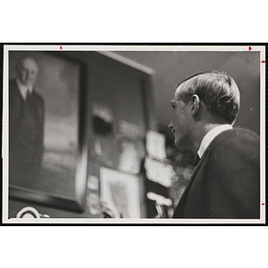 A male staff member looking up to see a portrait of a man