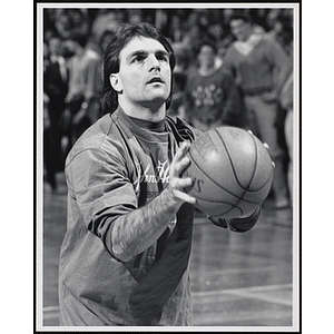 Former NFL player Doug Flutie holding a basketball and looking up at a fund-raising event held by the Boys and Girls Clubs of Boston and Boston Celtics