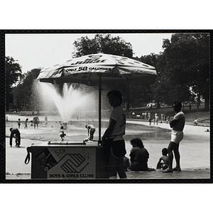 A teenage boy strikes a sideways pose with his ice juice cart on Boston Common