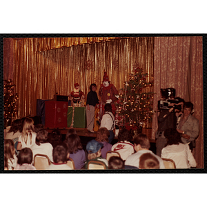 A clown speaks to an audience of children at a Christmas event