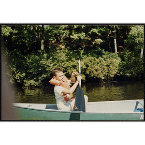 A boy paddles a canoe on a lake