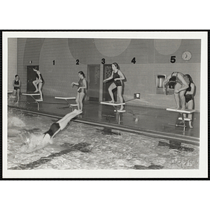 Teenage girls dive into a natatorium pool