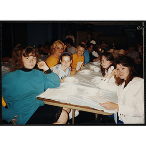 Children and women sit a table at an End of Year Party