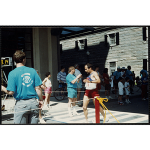 A man runs accross the finish line as race officals and spectaors look on during the Battle of Bunker Hill Road Race