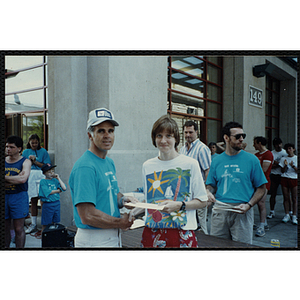 A man presents a woman with a certificate as he shakes her hand during the Battle of Bunker Hill Road Race