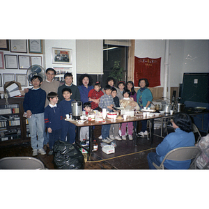 Adults and children pose for a group photo beside a buffet table during a Chinese Progressive Association holiday party