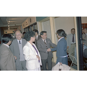 Member of the Consulate General of the People's Republic of China shakes the hand of a woman at a welcome party held for the Consulate General's visit to Boston