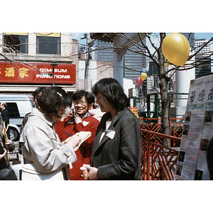 Suzanne Lee and another member of the Chinese Progressive Association exchange information with a pedestrian on the street in Boston's Chinatown