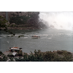 A wide view of a boat on the water in front of a waterfall at Niagara Falls