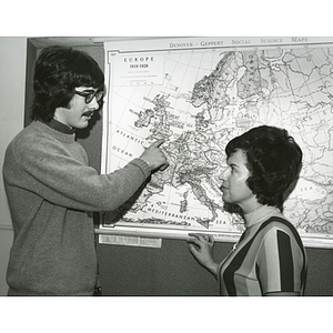 Student points at a map of Europe as Professor Caruso looks on