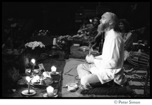 Ram Dass seated onstage at the Winterland Ballroom during his 'marathon,' addressing the audience