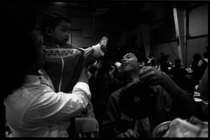 Cambodian New Year's celebration: man with baby holding cash, and drummer