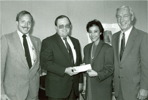 Deirdre Lin standing indoors with three unidentified men.