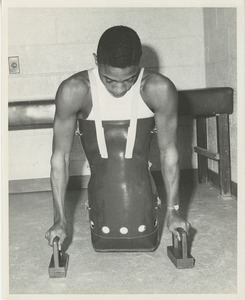 A double amputee wears a body prosthesis and uses floor handles to walk with his arms