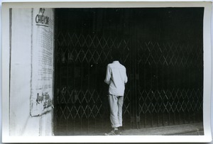 Man peering into gated bookstore, Hanoi