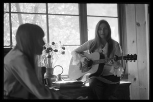 Judy Collins playing guitar, with Joni Mitchell in the foreground, taken at Mitchell's house in Laurel Canyon
