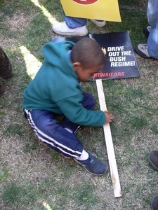 Young boy seated on the National Mall with a sign reading 'Drive out the Bush regime,' during the march against the War in Iraq