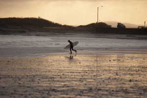 Surfer walking with his board toward the water
