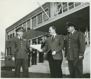 John Gillespie standing outdoors with two servicemen in uniform
