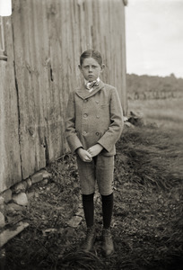 Young boy in good suit, in front of a barn (Greenwich, Mass.)
