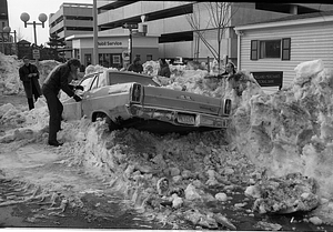 Unidentified man opening door of car buried in snow on Cambridge Street