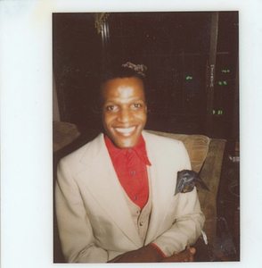 A Photograph of Marsha P. Johnson Wearing a White Jacket and Red Button-up