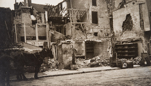 Horse-drawn wagon on the street in front of damaged buildings