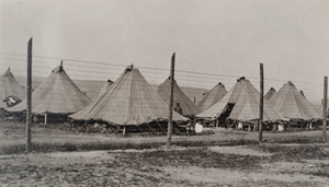 View of rows of tents in a German prisoners camp behind a high barbed wire fence