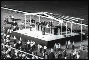 The Beatles performing at Suffolk Downs race track, police lined up in front of the stage