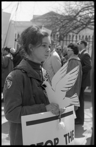 Woman holding a cutout cardboard peace dove and a sign reading 'Stop the killing', marching with antiwar demonstrators standing in front of the White House during the March on Washington