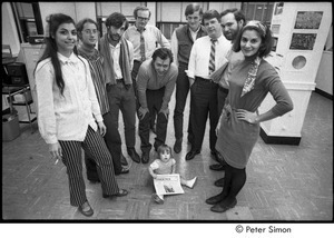 Staff of Cambridge Phoenix posing with a baby: Jean Grillo (left) ,Elliot Blinder (3rd from left), Robert Ventola (bending over), Jeffrey Tarter (2nd from right)