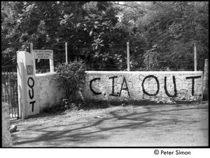 Gate by a water treatment plant with graffiti reading, 'C.I.A. OUT'