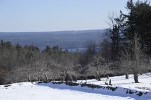 View of the Quabbin Reservoir over a stone wall and apple orchard at the south end of the New Salem Common