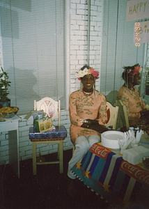 A Photograph of Marsha P. Johnson Sitting in a Chair in Front of a Mirror at Her Birthday Party