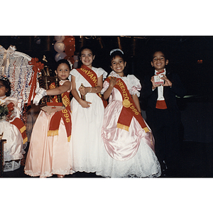 Three girls wearing sashes and a boy in a tuxedo at the Festival Puertorriqueño