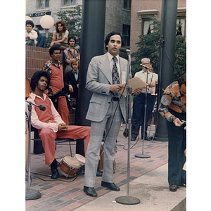 A man speaks into a microphone at an outdoor event