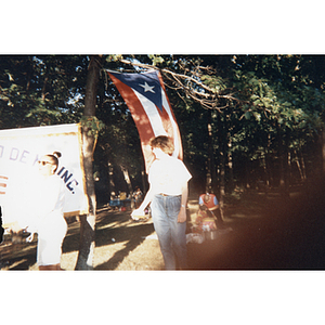 A woman stands in front of a Puerto Rican flag at a picnic event