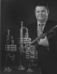 Walter Chesnut standing holding trumpet, with three trumpets in front of him