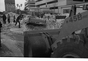 Pedestrians, cars, and construction equipment among snowbanks