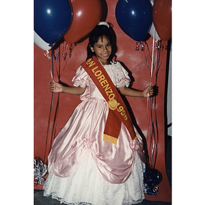 A girl wears a San Lorenzo 1996 sash and holds balloons at the Festival Puertorriqueño