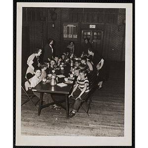 Women attend to a group of boys at a table during a Mothers' Club event