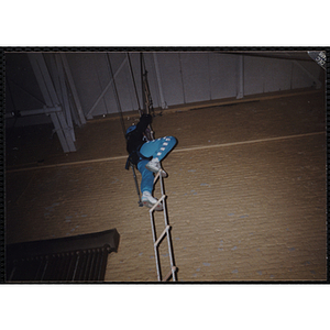 A child climbs to the top of a rope ladder in a gymnasium