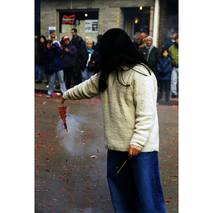 Woman holds a firecracker in the street during a celebration of the Chinese New Year in Boston's Chinatown