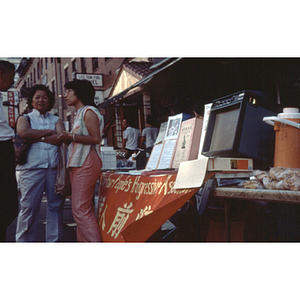 Suzanne Lee stands with other CPA members at a Chinese Progressive Association information table in Boston's Chinatown