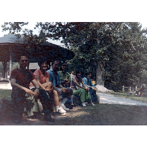Chinese Progressive Association members sit in a row in front of a gazebo in a wooded location