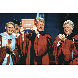 President Bill Clinton holds up his honorary degree at commencement