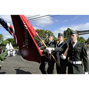 Four ROTC cadets carrying ceremonial rifles, the American flag, and the Northeastern University flag