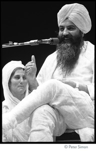 Yogi Bhajan on stage on the last night of the Kohoutek Celebration of Consciousness, with Hari Kaur Bird (?) beside him
