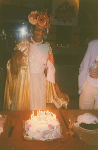 Photographs of Marsha P. Johnson Standing in Front of a Birthday Cake with Lit Candles